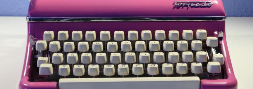 A bright pink Typewriter with white keys