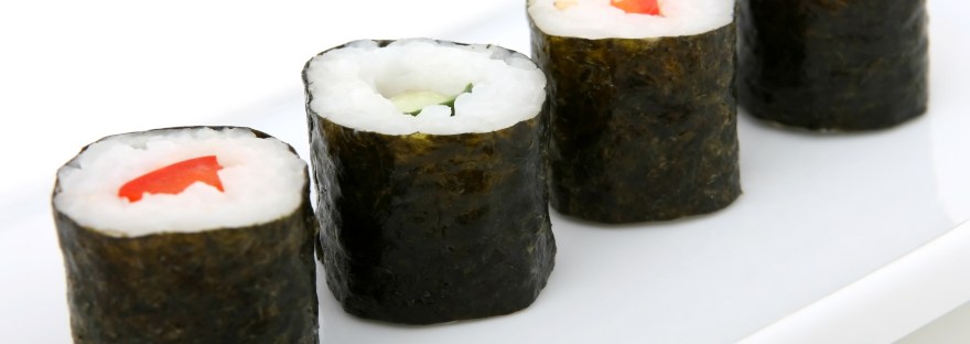 4 pieces of sushi on a white background - they are seaweed rolls with alternating pepper and cucumber filling