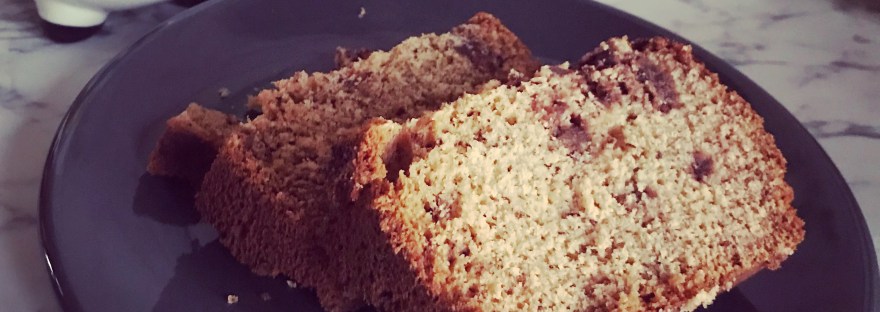 Banana Bread on a Grey Plate on marble with a unicorn cup in the background.